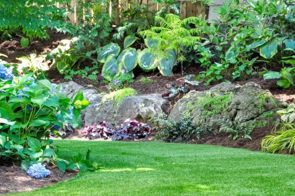 Jardin paysager avec pelouse soignée, allées structurées et massifs de fleurs colorés